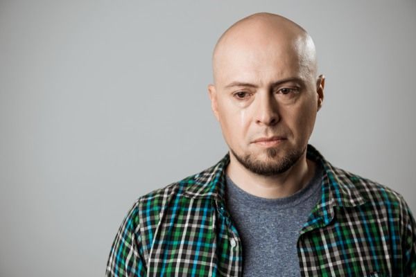 Retrato de homem bonito irritado pensando sobre parede bege