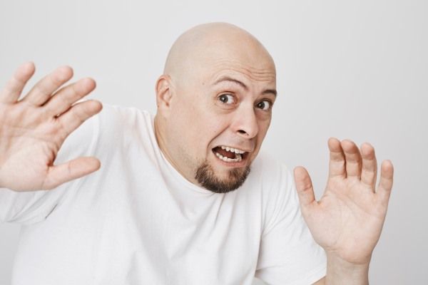 Close-up de um homem barbudo assustado e careca gritando