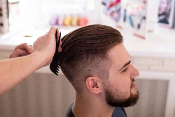 Homem moreno com um corte de cabelo elegante no fundo da barbearia