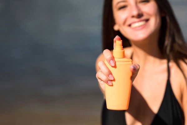 Mulher com protetor solar na praia