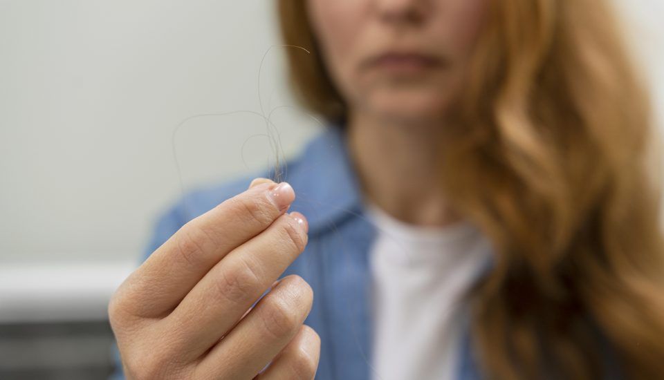 Tricofagia - mulher olhando para uma mecha de cabelo em sua mão