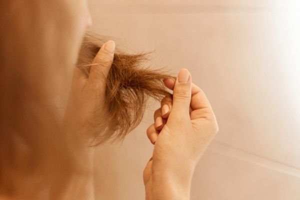Mulher verificando as pontas do cabelo - Tricofagia