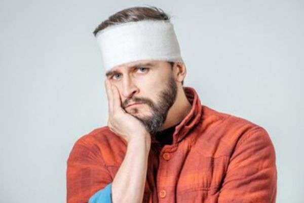 Retrato de homem com bandagens enroladas na cabeça, isolado em um fundo cinza