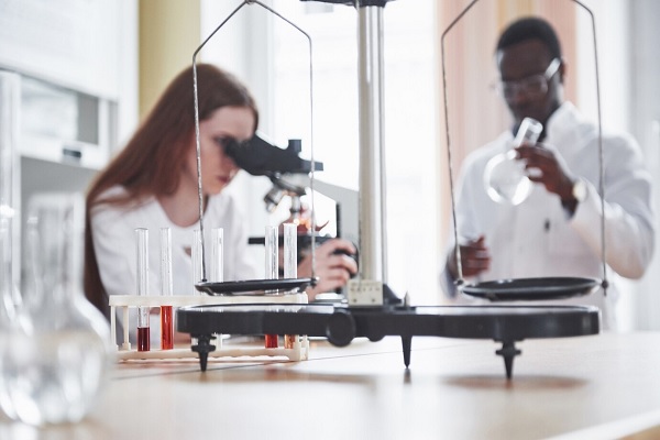Assistente de laboratório com lâmpada de vidro de laboratório de microscópio com produtos químicos.
