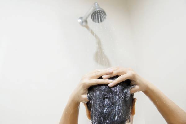 o sol danifica o cabelo - Mulher lavando o cabelo com cuidado depois de saber que o sol danifica o cabelo