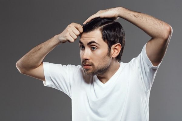 Jovem bonito penteando o cabelo