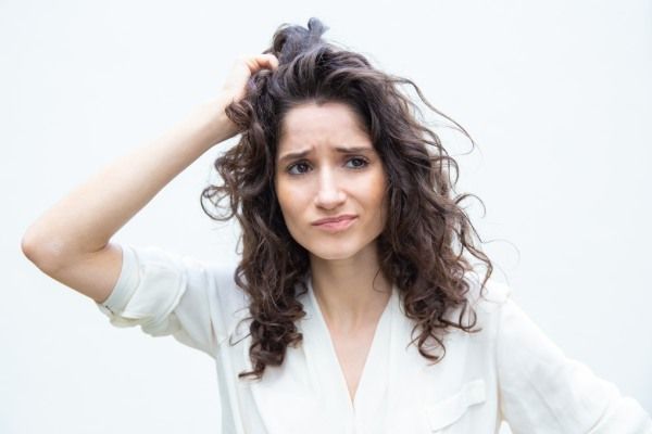 Mulher coçando o cabelo com tricorrexis nodosa 