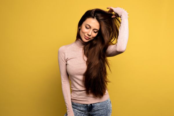 Garota pacificada com pulôver rosa ajeitando o cabelo