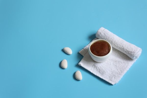 Composição de spa minimalista com esfoliador capilar natural e toalha sobre fundo azul, espaço de cópia