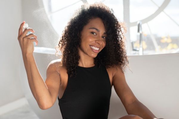 Mulher com cabelo afro aplica produtos para melhorar a densidade do cabelo cacheado