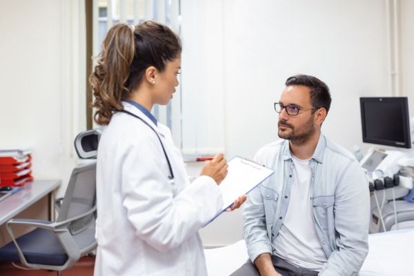 cabelo transplantado - Homem sério consultando com jovem médica médica na reunião de check-up no hospital
