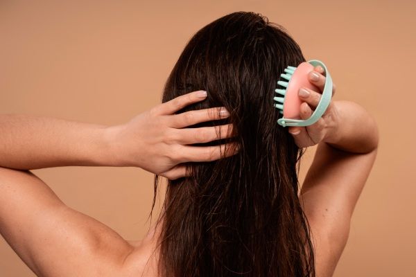 Mulher de altura média a dar-se uma massagem no couro cabeludo
