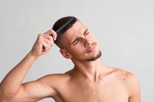 inflamação após o transplante capilar - Vista frontal de um homem sem camisa usando um pente