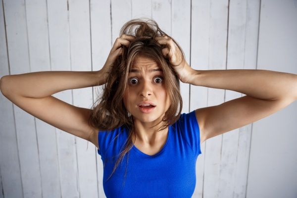 ácido salicílico para cabelo - mulher virada que guarda o cabelo cede a parede de madeira branca