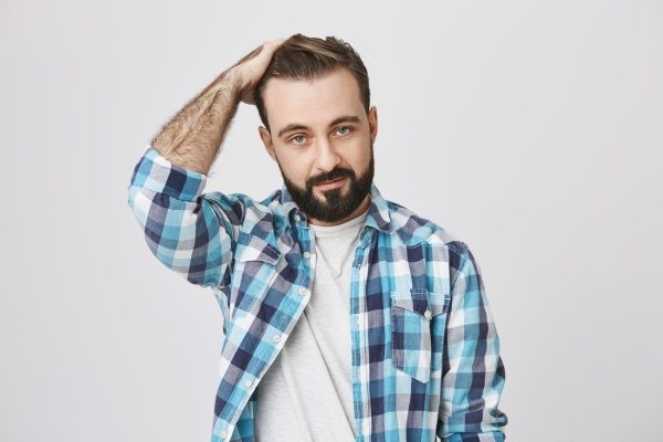 Homem barbudo bonito passa a mão pelo cabelo e parece atrevido