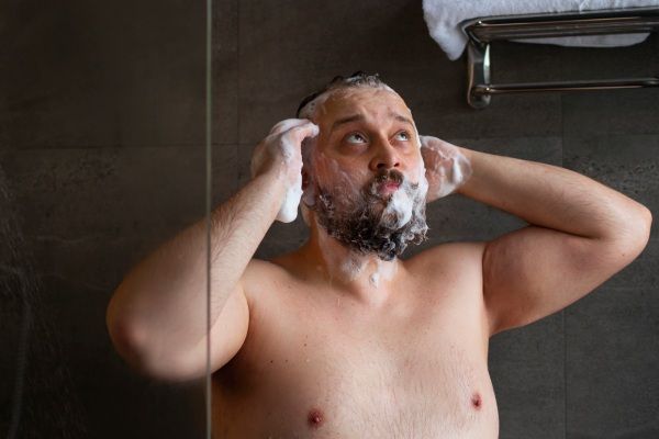 Homem realizando higiene após implante capilar