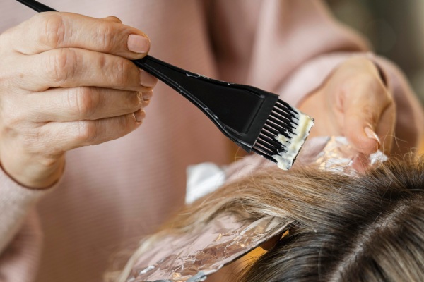 Mulher tendo o cabelo tingido em casa por esteticista