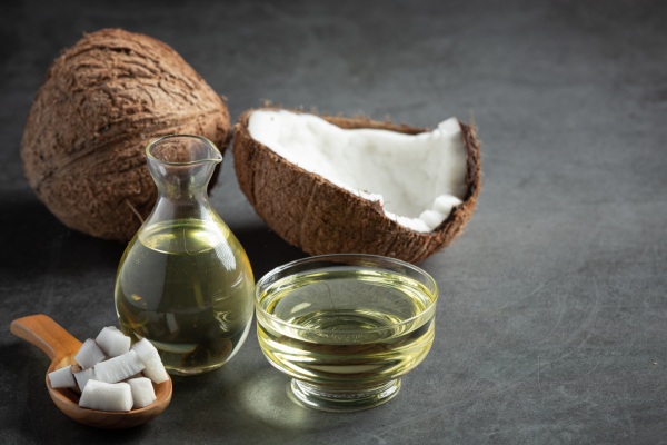 Jarra de óleo de coco com coco colocada em fundo escuro