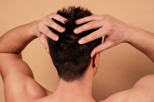 Homem de tiro médio a dar-se uma massagem no couro cabeludo