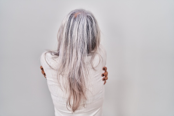 Mulher de meia-idade com cabelos grisalhos em pé sobre fundo branco abraçando-se feliz e positiva de trás para frente amor próprio e autocuidado
