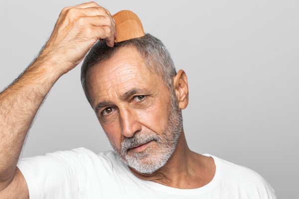homem penteia cuidadosamente seu cabelo implantado