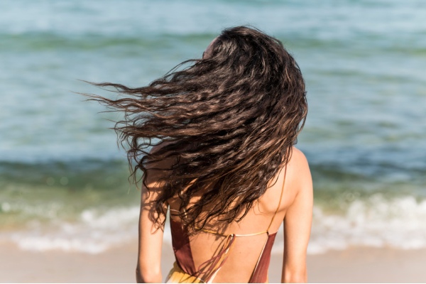 Como cuidar do cabelo no verão - menina na praia com o cabelo solto