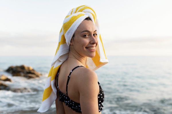 mulher curtindo a praia com uma toalha no cabelo