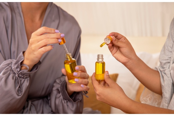 Mulheres segurando frascos de óleo para cabelo em suas mãos