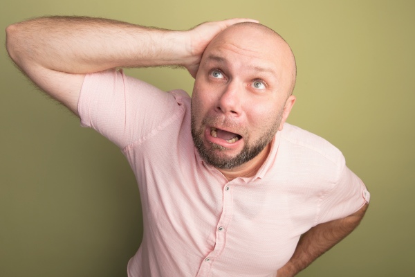 Falacrofobia - homem passando a mão na cabeça careca com um olhar preocupado