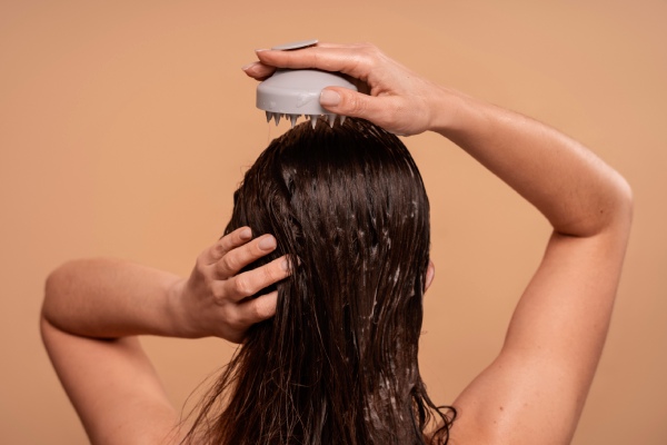 mulher lavando o cabelo com um massageador de couro cabeludo