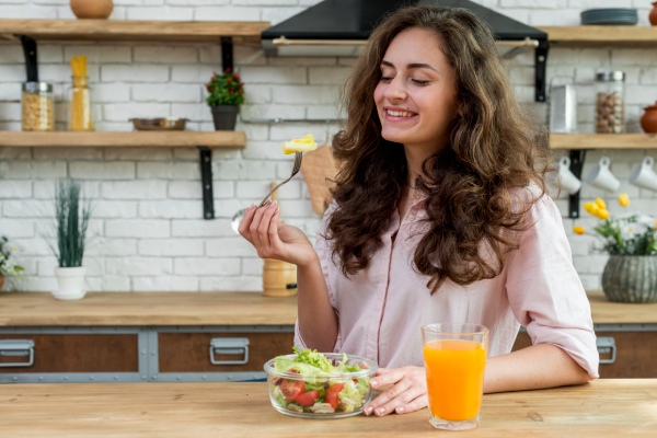 Queda cabelo - Mulher sorrindo enquanto come alimentos saudáveis