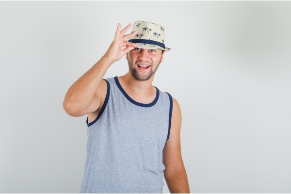 Homem com um chapéu protegendo um implante de cabelo do sol