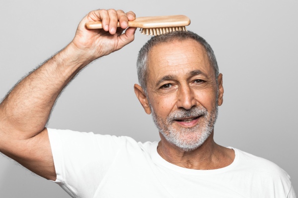homem idoso penteando a cabeça com uma linha de cabelo recuada