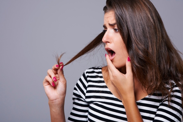 afinamento dos cabelos - mulher olhando para o cabelo com surpresa