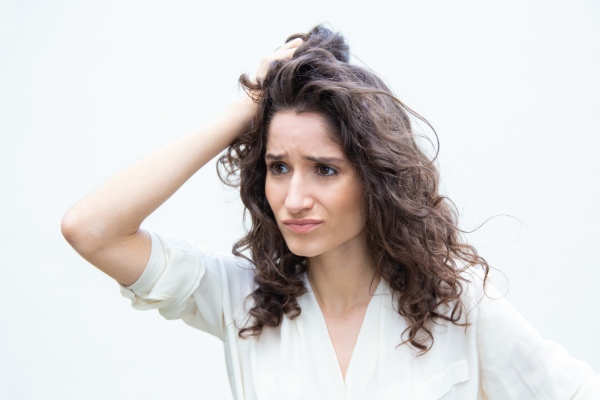 mulher passando a mão pelo cabelo, preocupada