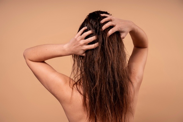 oleosidade excessiva no couro cabeludo - mulher passando as mãos pelos seus longos cabelos